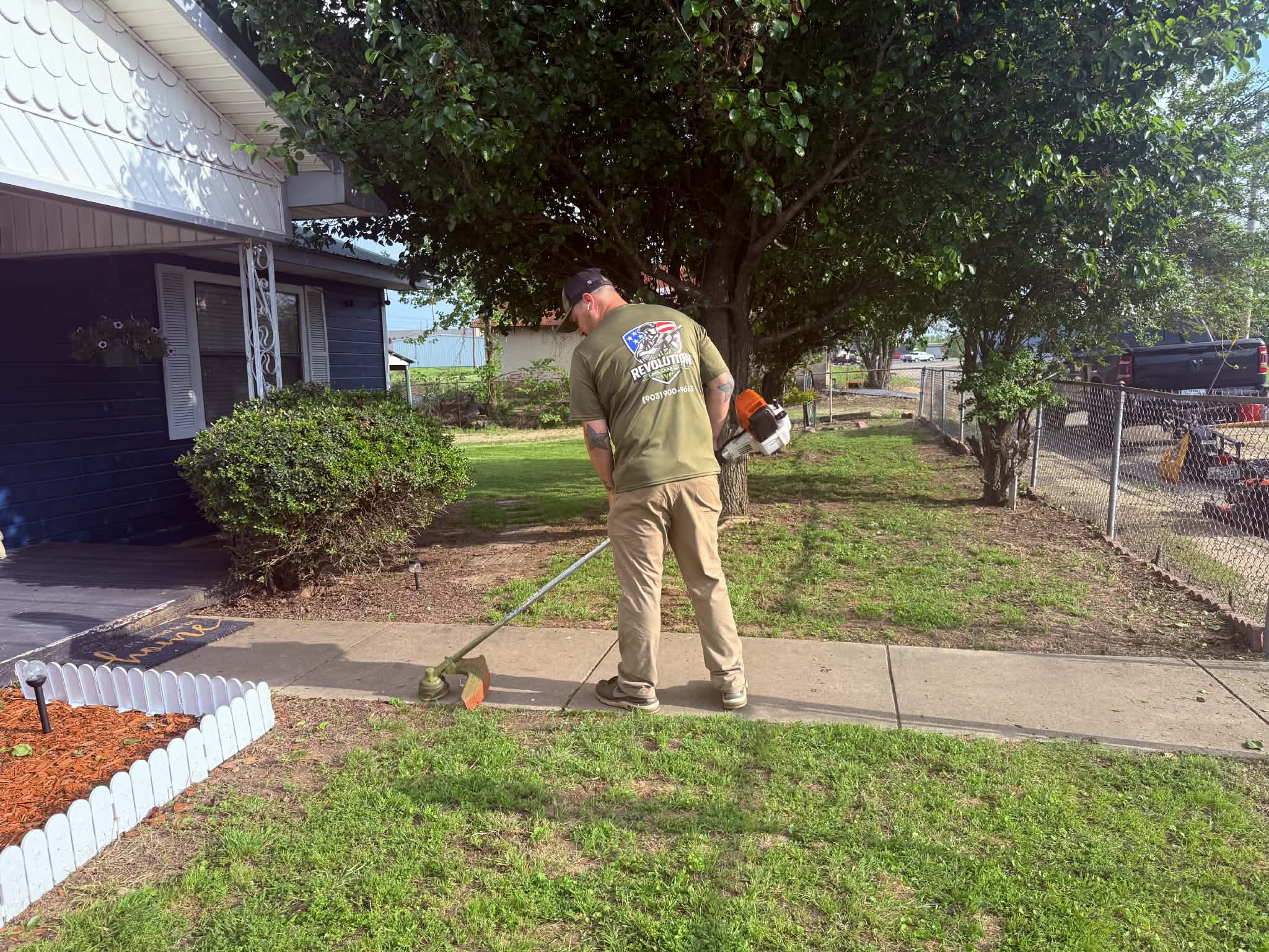Revolution Lawn Care crew member performing property maintenance